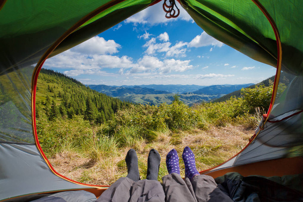 Vista de dentro de uma tenda em uma bela paisagem de mauntain. Turistas que jazem na tenda com vista para a paisagem montanhosa nas montanhas dos Cárpatos, Ucrânia
 - Foto, Imagem