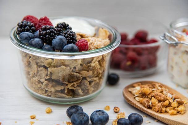 Jars full with granola, yogurt and fresh berries and wood spoon full whit granola, close-up, selective focus - Foto, Imagen