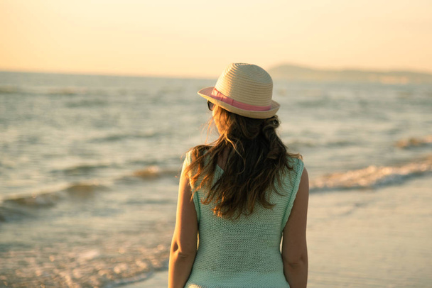 A girl on the beach at the sunrise, admiring and enjoying the sea breeze - Zdjęcie, obraz