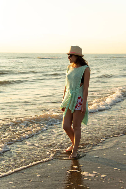 A girl on the beach at the sunrise, admiring and enjoying the sea breeze - Φωτογραφία, εικόνα