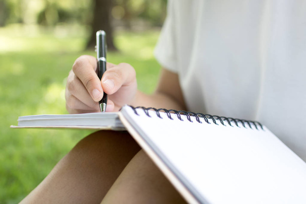 Frauen schreiben Gedächtnis auf Notizbuch auf grünem Gras  - Foto, Bild