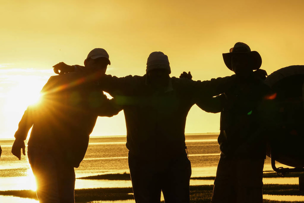 Siluetu muže back-lit nastavení slunce s rukama kolem jednoho a jiné - Fotografie, Obrázek