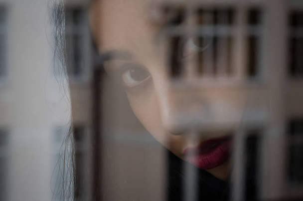 Young charming brunette girl behind a glass window - Fotografie, Obrázek