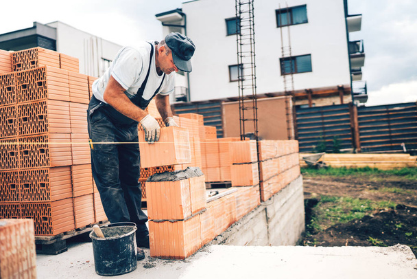 Industriële mason op bouwplaats werken met bakstenen en bouwen van muren. metselwerk details - Foto, afbeelding