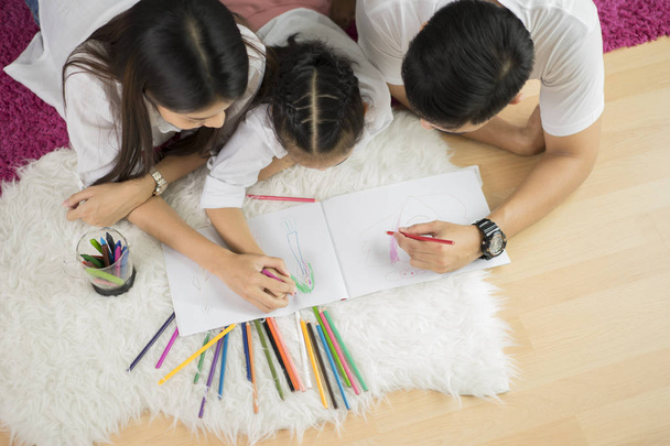 Молодая семья рисует вместе с красочными карандашами дома - Фото, изображение