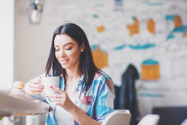 Woman in the cafe with a cup of coffee and macarons, soft focus background - Foto, afbeelding