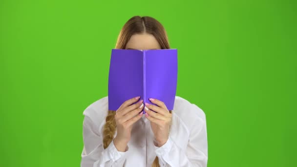 Schoolgirl covered her face with a notebook. Green screen - Filmagem, Vídeo