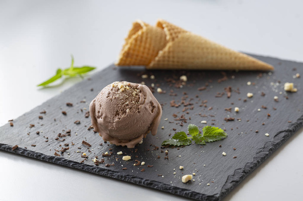 Шоколадное мороженое в вафельных рожках с орехами и кусочками темного шоколада
.  - Фото, изображение