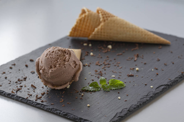 Chocolate ice cream in waffle cones, with nuts and pieces of dark chocolate.  - Valokuva, kuva