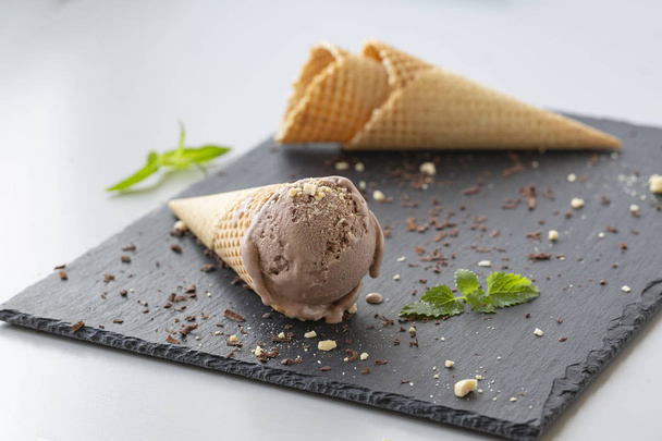 Chocolate ice cream in waffle cones, with nuts and pieces of dark chocolate.  - 写真・画像