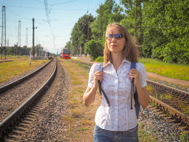 Woman traveler wearing backpack waiting railway at train.  - Photo, Image