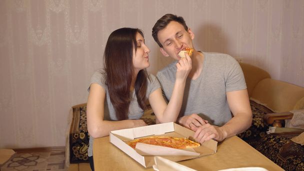 Morena mulher e homem comendo pizza em casa
. - Foto, Imagem