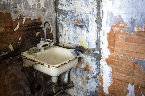 schmutzige alte Waschbecken vor dem Hintergrund aufgerissener Wände, das Konzept der Reparatur - Foto, Bild