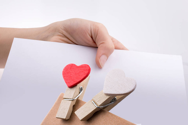 Hand holding a white sheet of paper with heart clips on it - Photo, Image