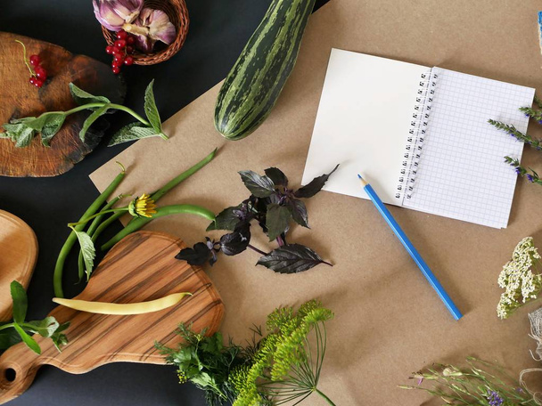 Запись рецептов, свежая зелень, овощи, цветы на разделочных досках, черная и коричневая оберточная бумага, вид сверху
 - Фото, изображение