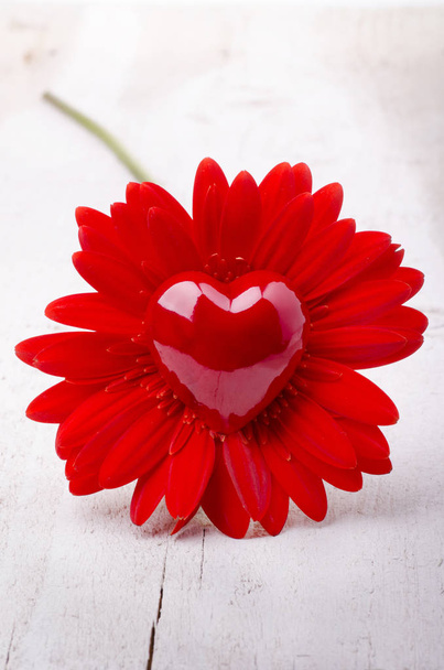 στον πρώτο όροφο του ένα όμορφο άνθος κόκκινο gerbera και σχήμα καρδιάς σε ανοιχτόχρωμο φόντο ξύλινη - Φωτογραφία, εικόνα