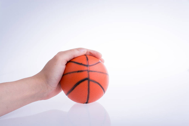 Ruka drží model oranžový basketbal na bílém pozadí - Fotografie, Obrázek