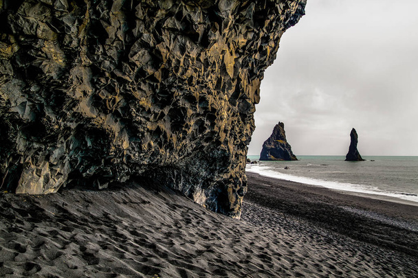 Praia de areia negra na Islândia, Reynisfjara Beach, perto de Vik. Rochas e penhascos de basalto na praia oceânica. Um ponto turístico popular na costa sul da Islândia
. - Foto, Imagem
