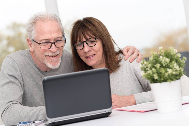 Couple mature utilisant un ordinateur portable à la maison
 - Photo, image