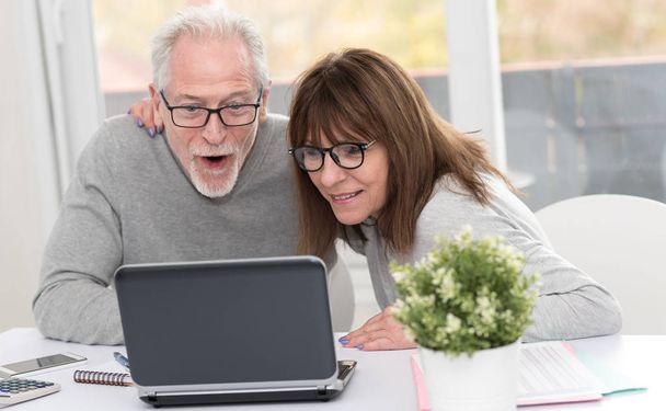 Gelukkig ouder paar hebben een geweldige verrassing op laptop - Foto, afbeelding