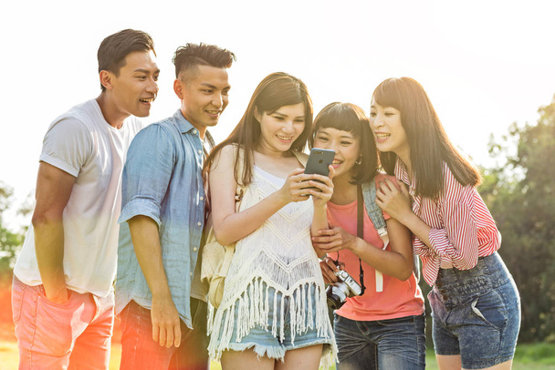 Asian people look something at cellphone with his friends in the park - Фото, изображение