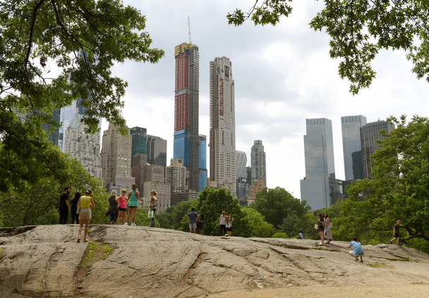 New York, USA - May 26, 2018: People in Central Park and skyscrapers of the Manhattan at the background. - Foto, afbeelding
