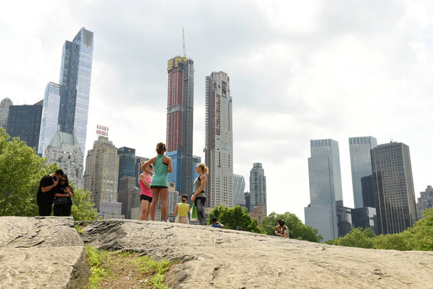 New York, USA - May 26, 2018: People in Central Park and skyscrapers of the Manhattan at the background. - Фото, изображение
