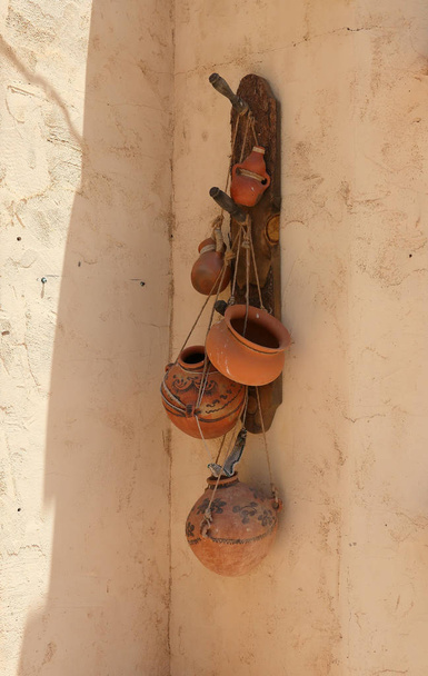 Terra cotta potten opknoping op de duistere kant van de muur van een adobe - Foto, afbeelding