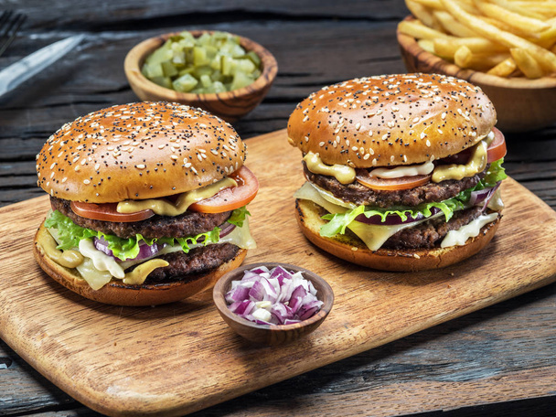 Hamburgers and French fries on the wooden tray. - Foto, afbeelding