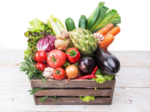 Fresh multi-colored vegetables in wooden crate. White background. - 写真・画像