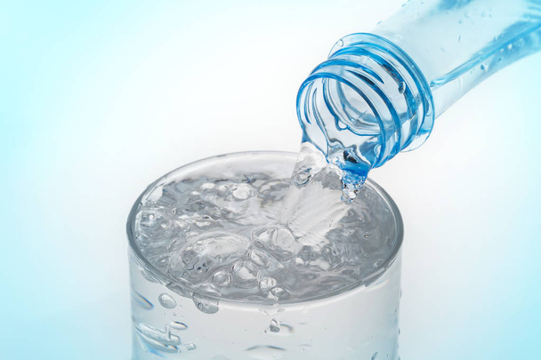 Versare acqua dalla bottiglia in vetro su fondo blu
 - Foto, immagini