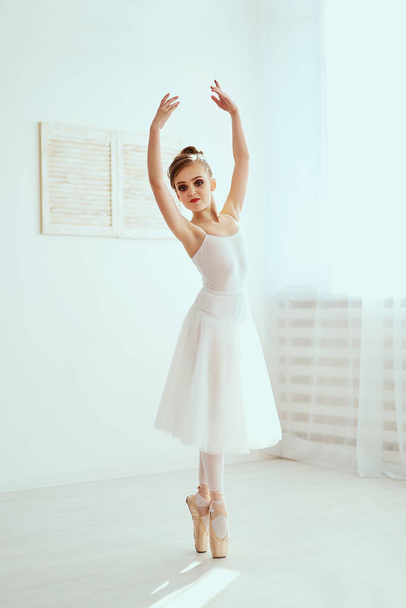 Красива балерина позує і танцює в білій студії, повній світла. Фото значно відображає незрівнянну красу класичного балетного мистецтва
. - Фото, зображення