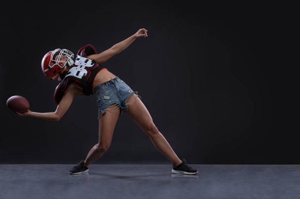 Σεξουαλική γυναίκα sportive τρέξιμο με μπάλα του ράγκμπι και ουρλιάζοντας επιθετικά σε μαύρο φόντο. Αντιγράψτε το χώρο. ισότητα των φύλων - Φωτογραφία, εικόνα