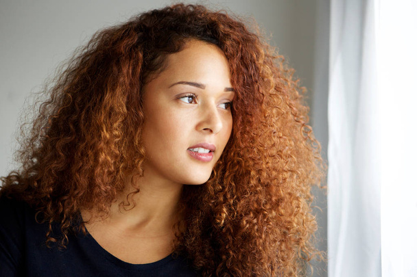 Close up portrait of beautiful woman with curly hair looking away - 写真・画像