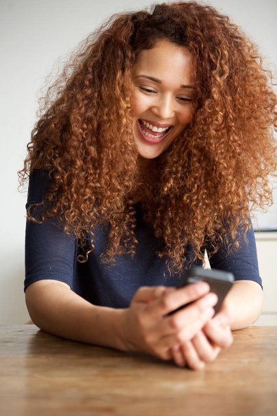 Портрет счастливой молодой женщины, смотрящей в мобильный телефон
 - Фото, изображение