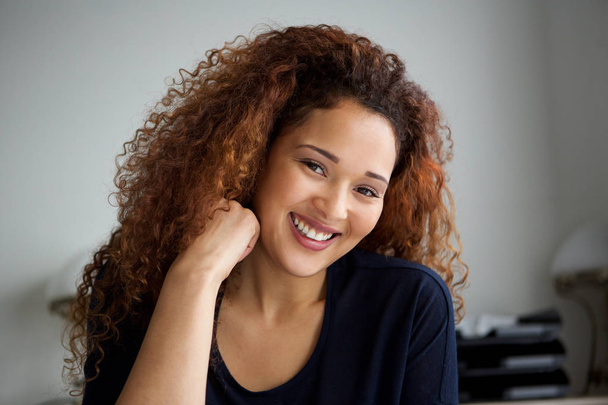 Nahaufnahme Porträt einer glücklichen jungen Frau mit lockigem Haar, die lächelt - Foto, Bild