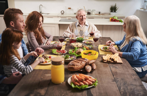 Delightful family eating together in kitchen - Zdjęcie, obraz