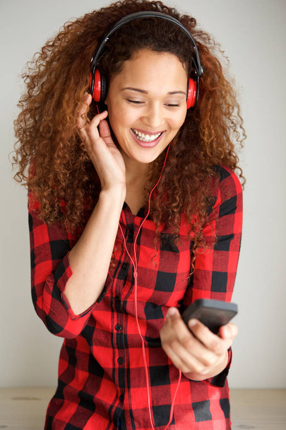 Portrait of young woman listening to music with mobile phone and headphones - Photo, Image