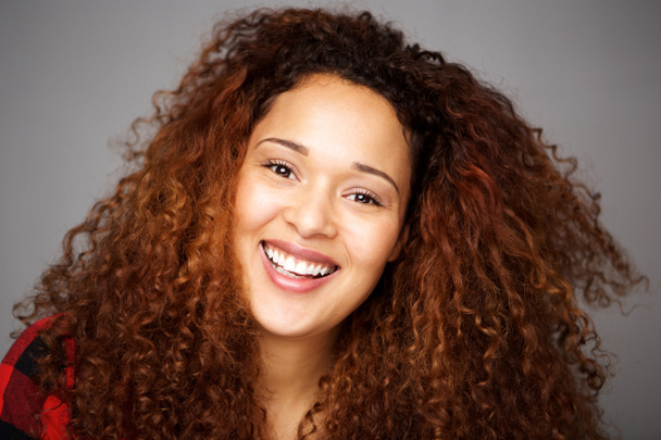 Gros plan portrait de heureuse jeune femme afro-américaine avec les cheveux bouclés contre le mur gris
 - Photo, image