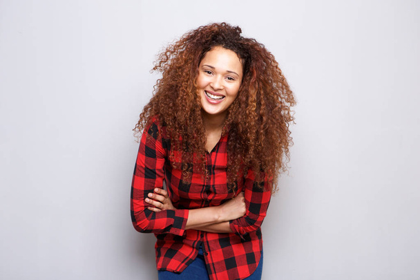 Портрет счастливой молодой женщины с вьющимися волосами, улыбающейся на сером фоне
 - Фото, изображение