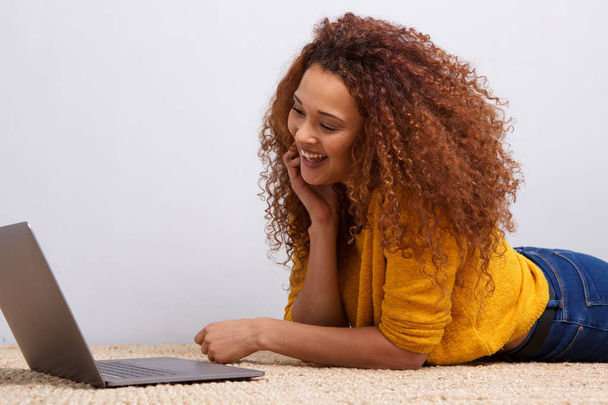 Портрет молода жінка лежить на підлозі і, дивлячись на екран ноутбука - Фото, зображення