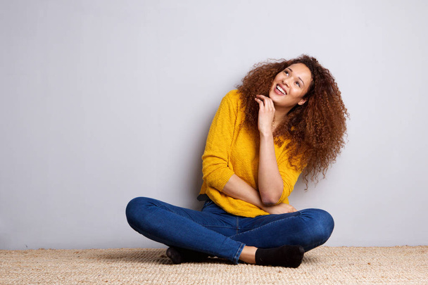 Портрет веселой молодой женщины, сидящей на полу и смеющейся
 - Фото, изображение