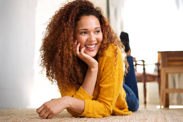 Portrait of happy young woman lying on floor at home and laughing - Foto, Bild