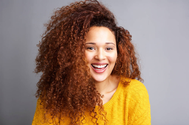 Gros plan portrait de heureuse jeune femme aux cheveux bouclés riant sur fond gris
 - Photo, image