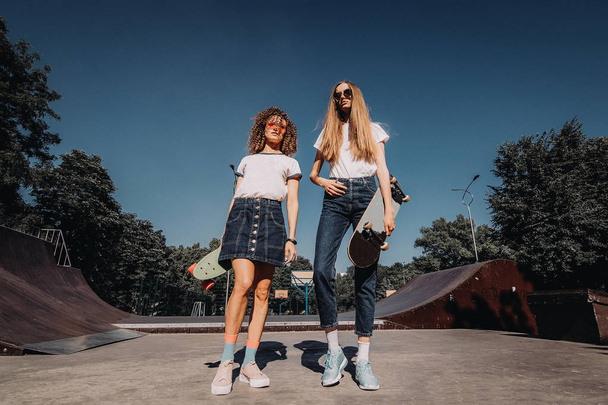 Gelukkig vriendinnen loopt over skateboard oprit. Twee vrouwelijke schaatsers genieten van op Skatepark. - Foto, afbeelding