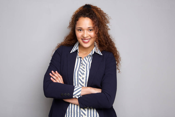 Retrato de mujer de negocios con el pelo rizado sonriendo sobre fondo gris
 - Foto, imagen