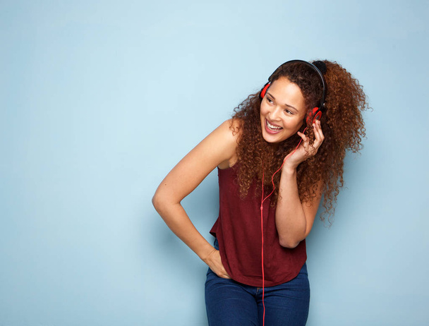 Portrait of young woman with curly hair listening to music with headphones - 写真・画像