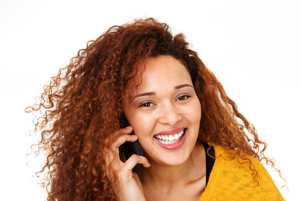 Close up portrait of beautiful young woman with curly hair talking on mobile phone against isolated white background - Zdjęcie, obraz
