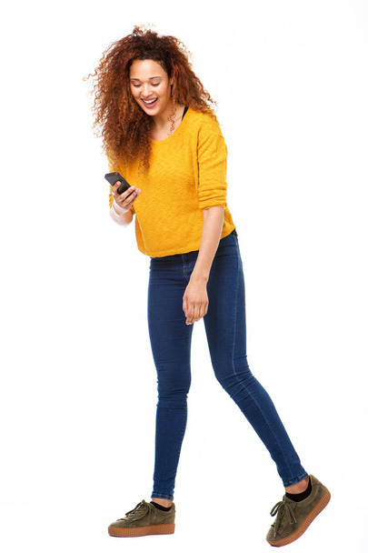 Full body portrait of happy woman looking at cellphone against isolated white background - Photo, Image
