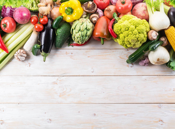 Different colorful vegetables arranged as a frame. Wooden background. - 写真・画像
